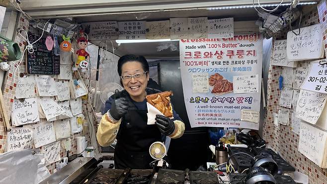 An owner of crossaint bungeoppang stall poses for a photo each time before hadning out a croissant bungeoppang. [WOO JI-WON]