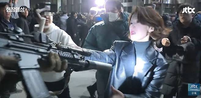 Ahn Gwi-ryeong, a spokesperson for the liberal Democratic Party, grabs the weapon of a soldier stationed in front of the National Assembly in Yeouido, western Seoul, on Dec. 3, 2024. [SCREEN CAPTURE]