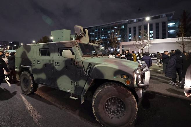 지난해 12월 4일 새벽 서울 여의도 국회 앞 계엄군 차량 뒤로 군 헬기가 경내로 비행하고 있다. 2024.12.4 뉴스1