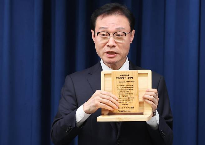 이규연 홍보소통수석이 3일 서울 용산 대통령실 청사에서 열린 5부 요인 초청 오찬 관련 브리핑에서 ‘빛의 민주주의 꺼지지 않는 기억패’를 들어 보이고 있다. 이재명 대통령은 이날 오찬에서 우원식 국회의장으로부터 지난해 12월 3일 계엄군에 의해 부서졌던 국회 집기들을 재활용해 만든 ‘기억패’를 전달받았다. 뉴스1