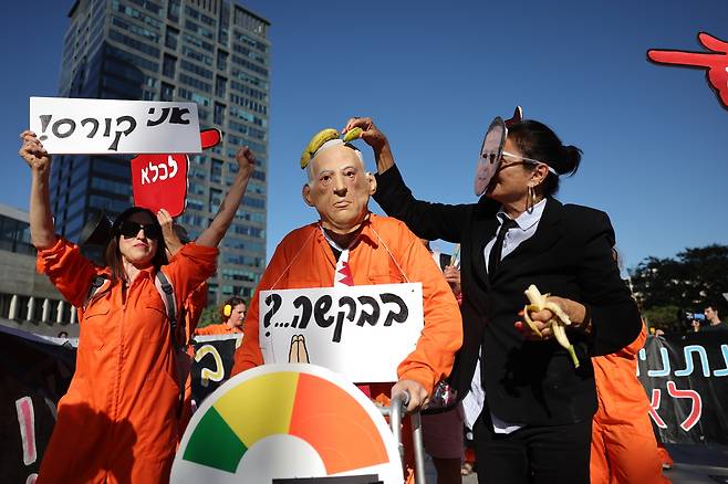 1일(현지시간) 이스라엘 텔아비브 지방법원베냐민 네타냐후 이스라엘 총리의 사면 신청에 항의하는 시위가 열린 가운데, 네타냐후 총리와 이츠하크 헤르조그 대통령으로 분장한 시위대가 ‘Please(부탁한다)’라는 문구가 적힌 피켓을 들고 항의하고 있다. EPA연합뉴스