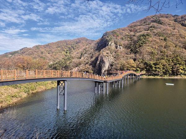 전남 담양군 용면 담양호 수변산책로인 용마루길과 비네산~과녁바위산을 찾았다. 담양호국민관광단지에서 탐방객들이 용마루길을 타려고 호수를 가로지른 나무다리를 건너고 있다. 사진에는 안 보이지만 오른쪽 봉우리 뒤편에 과녁바위산이 있다.