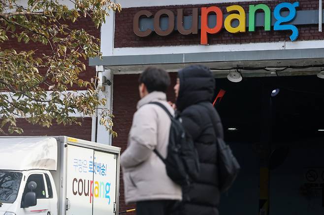 Pedestrians walk past a Coupang logistics center in Seoul on Dec. 2. [YONHAP]
