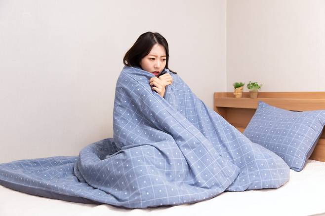 침대 위에서 추위에 떨고 있는 사람.[게티이미지뱅크]