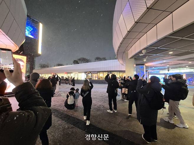 4일 오후 서울 강남구 코엑스에서 올해 첫눈이 내리자 시민들이 발걸음을 멈추고 사진을 찍고 있다. 김태욱 기자