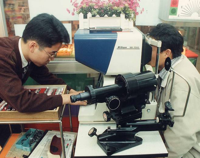 A liscensed optician conducts an eye exam on a customer [JOONGANG ILBO]
