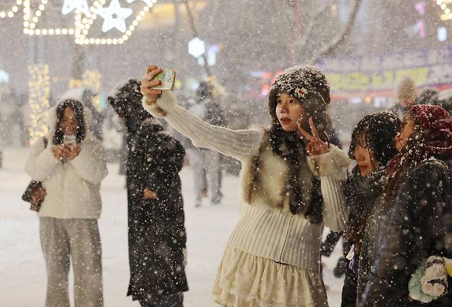 지난 4일 서울 마포구 홍대 부근에 눈이 내리는 가운데 외국인 관광객들이 기념사진을 촬영하고 있다. <연합>