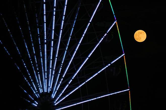 [니코시아=AP/뉴시스] 4일(현지 시간) 키프로스 니코시아 도심에서 올해 마지막 보름달인 슈퍼문이 크리스마스 마켓 대관람차 뒤로 떠오르고 있다. 2025.12.05.