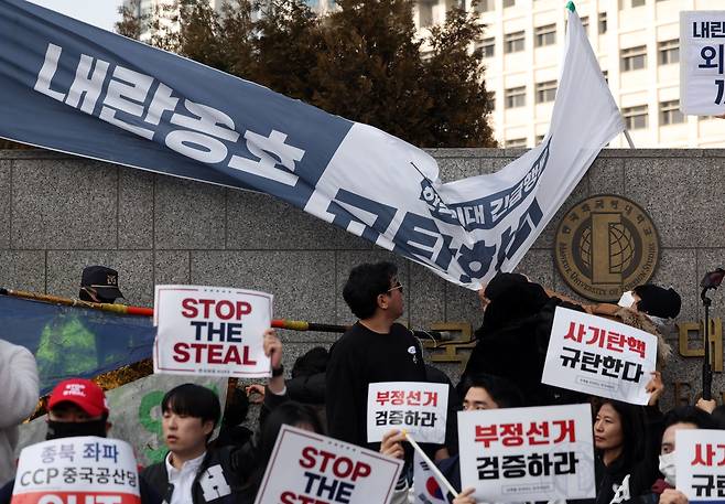 A supporter of President Yoon Suk Yeol pulls down a pro-impeachment banner during a far-right rally near the main gate of Hankuk University of Foreign Studies in Seoul in February this year. (Newsis)
