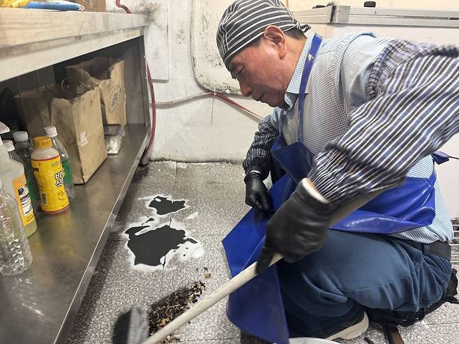 구석구석 들어가 있는 부스러기를 쓸어내는 김씨의 모습. 김씨가 서 있는 자리의 타일의 칠이 벗겨져 까맣게 된 모습이다. 백재연 기자