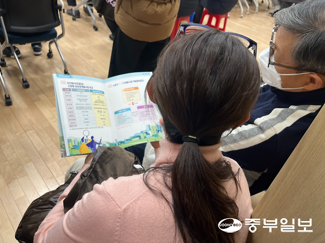 수원도시공사가 나눠준 고등1동 공공재개발사업 팜플렛을 보고 있는 주민들. 천민형기자