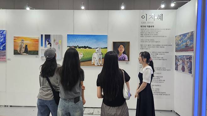 올해 7월 ‘북한이탈주민의 날’을 맞아 서울 강남구 코엑스에서 열린 ‘탈북 청년 작가 5인 전시회’에서 이지혜 씨(오른쪽)가 관람객들에게 자신의 그림을 설명하고 있다.