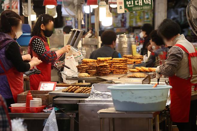 Street stall vendors at Gwangjang Market in Jongno District, central Seoul, flip jeon (savory pancakes) in this file photo from April 27, 2022. [YONHAP]