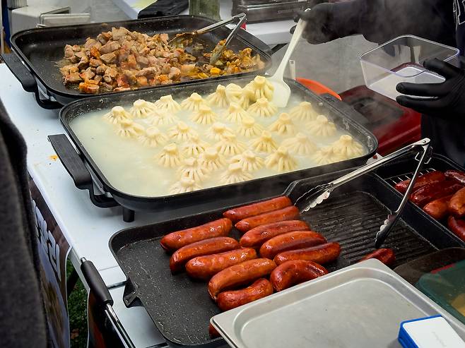 From left: Ojakhuri, a dish of cooked pork and potatoes, khinkali soup dumplings and kupati sausages are almost ready to be served to patrons at the Georgian booth of the European Market in Seongbuk District, central Seoul, on Dec. 6. [MICHAEL LEE]
