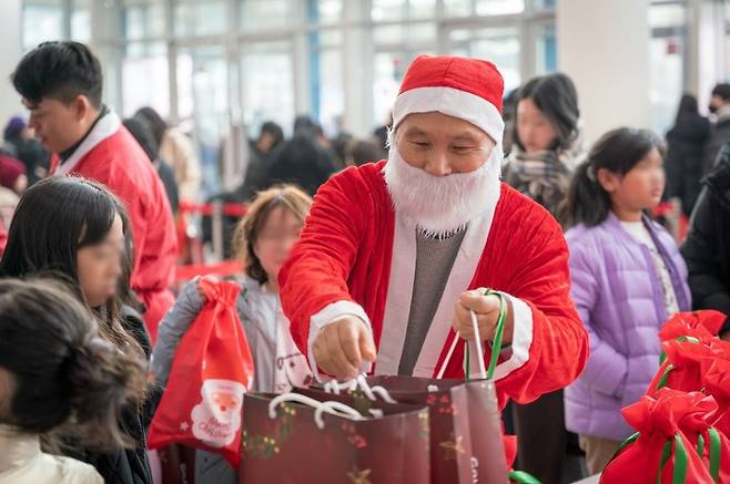 골프존문화재단이 6일 주최한 '2025 희망행복나눔 페스티벌'에서 산타 복장을 한 골프존문화재단 김영찬 이사장이 아이들에게 선물을 나눠주고 있다.