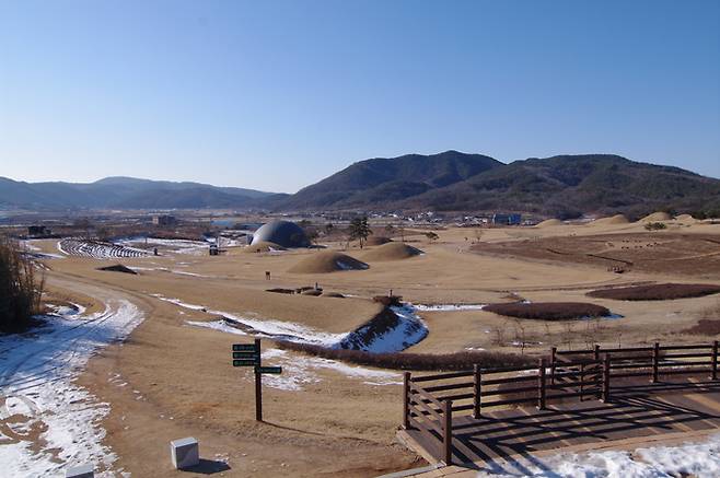 ▲ 경북 의성군 금성면 조문국사적지에서 겨울철 얕게 쌓인 눈과 누런 갈대빛이 고분군의 곡선을 따라 펼쳐지는 풍경을 담아, 사적지 내부 탐방로·전망데크·조문국박물관 돔형 건물의 배치를 계절 대비로 강조한 장면이 촬영됐다. 의성군
