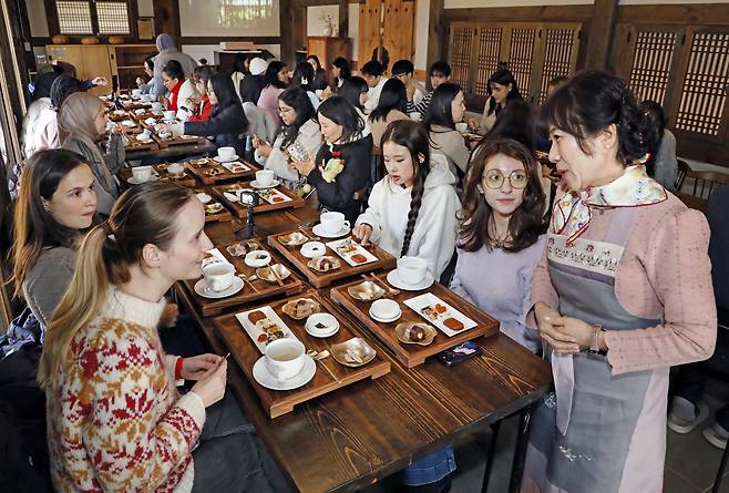 Kim Jung-hee, wife of Oh Kyeong-young, the sixth-generation descendant of the first owner of Ssangsanjae Hall, explains about the desserts to students on Dec. 2. [PARK SANG-MOON]