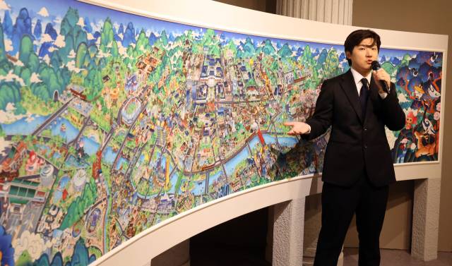 일제강점기를 거치지 않고 부국강병을 이룬 서울의 모습을 쿠키런 그림체로 그린 ‘꺼지지 않을 희망의 빛’ 작품을 조길현 데브시스터즈 대표가 설명하고 있다. 가운데 경복궁·덕수궁 등이 보인다. 뉴스1