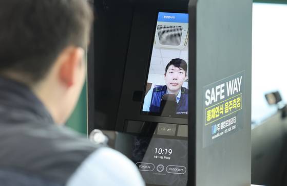 A driver measures his alcohol intoxication level using a facial and iris detection machine at a demonstration held at a bus garage in Busan in September. [YONHAP]