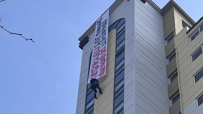 10일 오후 1시쯤 전남 나주시 빛가람동의 한 아파트 18층 높이에서 50대 남성 A씨가 체불임금 지급을 촉구하는 현수막을 내걸고 공중에 뜬 채로 고공농성을 벌이고 있다. 전남도소방본부 제공