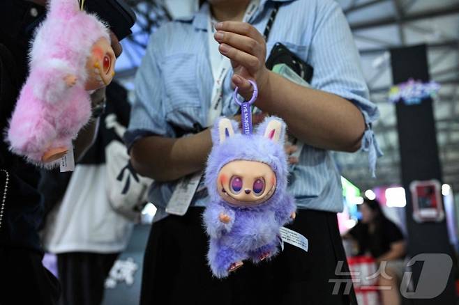 지난 8월 4일 상하이 신국제박람센터에서 열린 중국 디지털 엔터테인먼트 박람회 '차이나조이(ChinaJoy)'에서 한 여성이 라부부 인형을 방문객들에게 판매하고 있다. /AFPBBNews=뉴스1