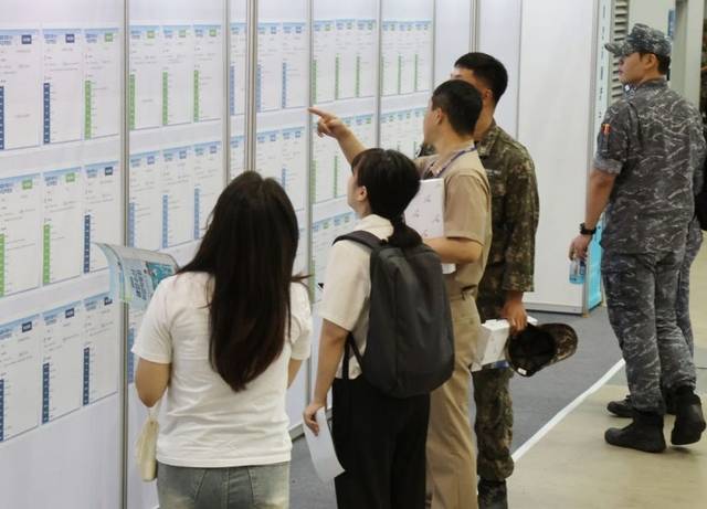 취업 박람회에서 채용 공고 보고 있는 구직자들. [연합뉴스]