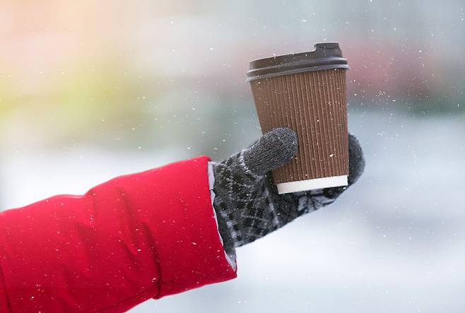눈이 내리는 겨울날 따뜻한 커피를 들고 있는 모습. 게티이미지뱅크