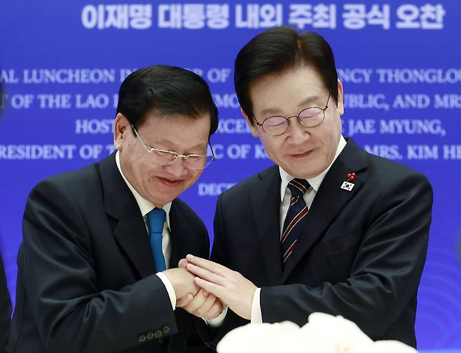 이재명 대통령이 15일 용산 대통령실에서 열린 한-라오스 공식오찬에서 통룬 시술릿 라오스 국가주석과 건배 후 손을 맞잡고 있다. [연합]
