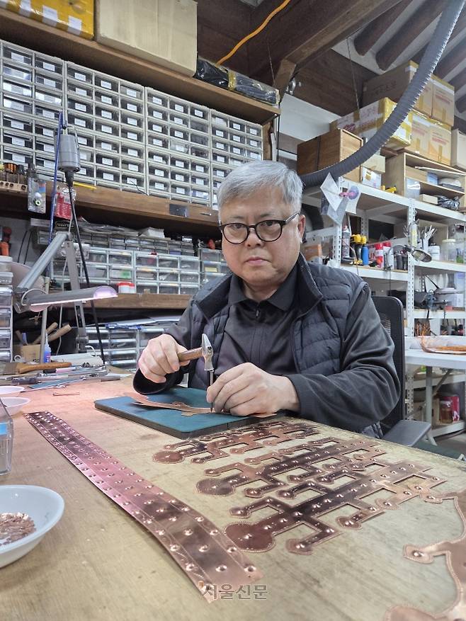 금속공예 명장 김진배 대표가 경북 경주시 하동 민속공예촌에 있는 자신의 공방 ‘삼선방’에서 금관 모형 제작을 위해 동판을 세공하고 있다.