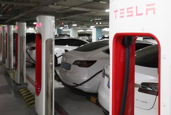 Teslas are charged at a station in downtown Seoul. [YONHAP]