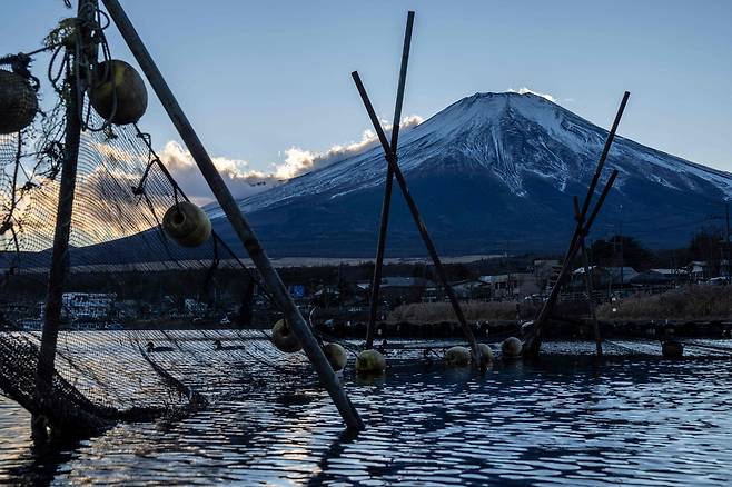 지난 5일 일본 야마나시현 야마나카호수에 세워져 있는 어구들 너머로 후지산의 모습이 보인다. AFP연합뉴스