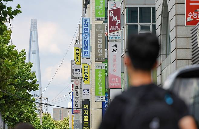 A person walks past private cram schools in Dogok-dong, Gangnam District, southern Seoul, on July 23. [WOO SANG-JO]