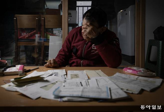 2년 전 30대 여성에게 휴대전화와 통장을 뺏긴 뒤 빚더미에 앉은 치매 환자 문영식(가명·76) 씨가 추심 서류와 미납 고지서를 보며 머리를 감싸고 있다. 혼자 사는 그는 노리기 쉬운 ‘먹잇감’이었지만, 후견인 등 제도의 보호를 받지 못했다.