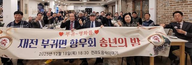 윤석정 재전진안군향우회장(맨 앞줄 왼쪽 2번째, 붉은색 넥타이), 진안 부귀면 재전향우회 장정섭 회장(맨 앞줄 왼쪽 3번째, 진청색 넥타이), 원현주 부귀면장(4번째) 등 향우회원과 내빈 등이 지난 18일 2025년송년의밤 행사에서 “사랑해요, 부귀”를 외치며 기념사진을 찍고 있다. / 사진=국승호 기자