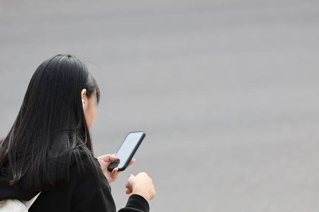 서울 시내 한 중학교에서 혼자 하교하는 학생이 스마트폰을 사용하는 모습. 연합뉴스