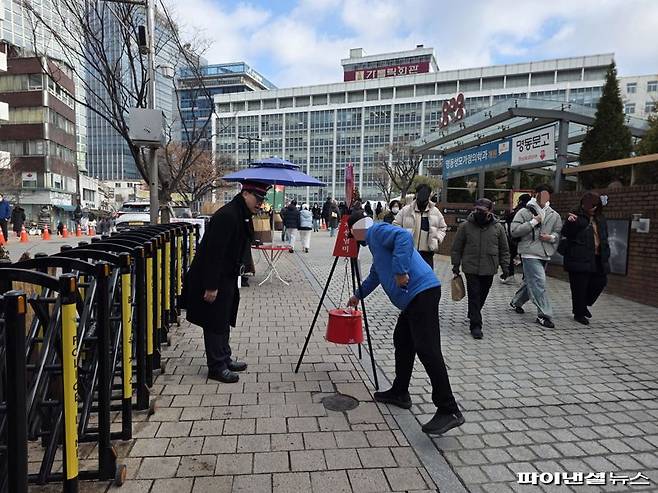 24일 오후 서울 중구 명동성당 앞에 마련된 구세군 자선냄비에 한 시민이 지폐를 넣고 있다. 사진=박성현 기자