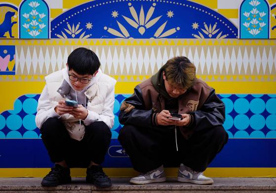 지난 11월 중국 상하이의 한 거리에서 두 남성이 스마트폰을 보고 있다. EPA=연합뉴스