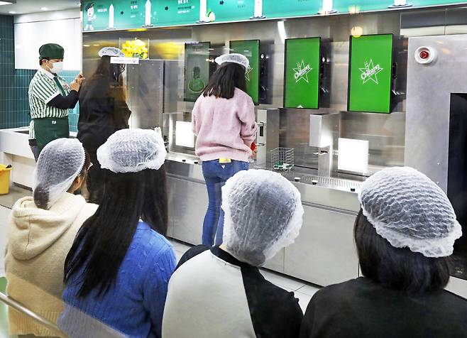 Adult participants experience how bottled beverages are made through role-playing at KidZania in Jamsil, southern Seoul, on Dec. 20. [PARK SANG-MOON]