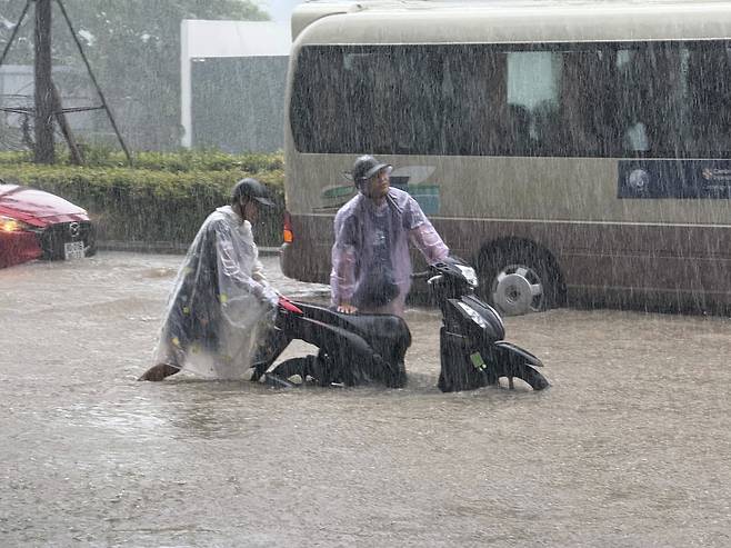 지난 8월 26일(현지시간) 태풍 카지키로 인해 홍수가 발생한 베트남 하노이에서 시민들이 오토바이를 밀고 있다. AP연합뉴스