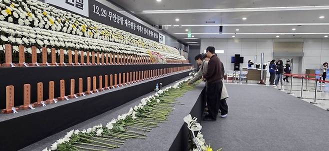 29일 전남 무안국제공항 1층에 마련된 12·29 무안공항 제주항공 여객기 참사 분향소에 추모객들이 헌화하고 있다. 민찬기 기자