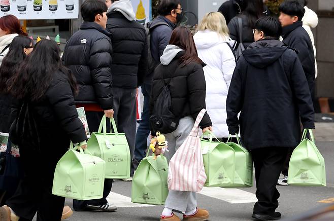 지난 23일 오전 대전 중구 성심당 케이크부띠끄에서 크리스마스 한정 케이크 ‘딸기시루’와 신제품 ‘말차시루’를 구매한 시민들이 두 손 가득 케이크 상자를 들고 매장을 나서고 있다. /신현종 기자