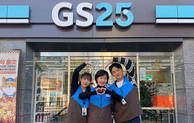 GS25의 가맹 경영주(가운데)와 영업관리자(OFC)가 매장 앞에서 하트를 그리고 있다.ⓒGS25