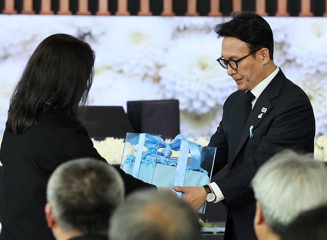 Prime Minister Kim Min-seok (right) receives a box of letters from the bereaved families of the victims in the deadly Jeju Air crash last year, at a commemoration of the accident held at the Muan International Airport on Monday. (Yonhap)