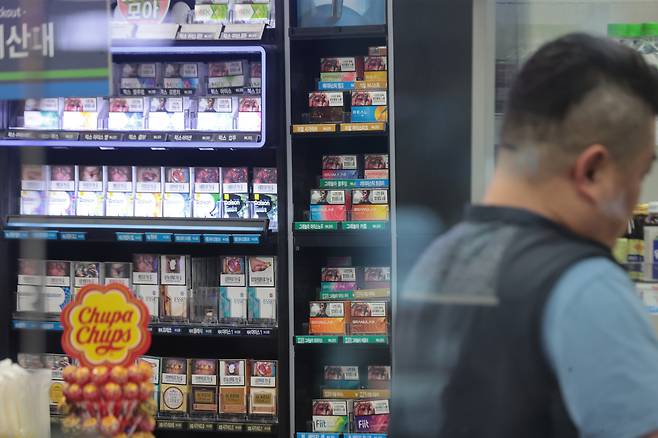 A convenience store worker is seen in front of a display of cigarettes and vapes at a store in Seoul on June 12. [YONHAP]