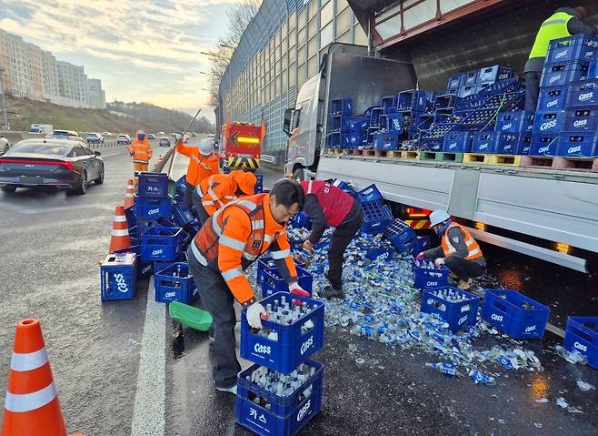 Korea Expressway Corp. employees clean up spilled beer bottles on the expressway ramp in Gwangju on Tuesday. (Korea Expressway Corp.)