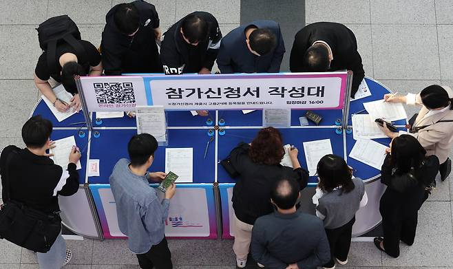 Job seekers are seen filling out application forms at a job fair held at Bexco in Busan on Oct. 27. [SONG BONG-GEUN]