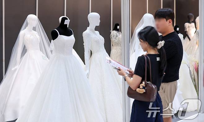 서울 강남구 삼성동 코엑스에서 열린 2025 추계 웨덱스 웨딩 박람회에서 예비 부부들이 전시된 드레스를 살펴보고 있다. 2025.7.6/뉴스1 ⓒ News1 김성진 기자