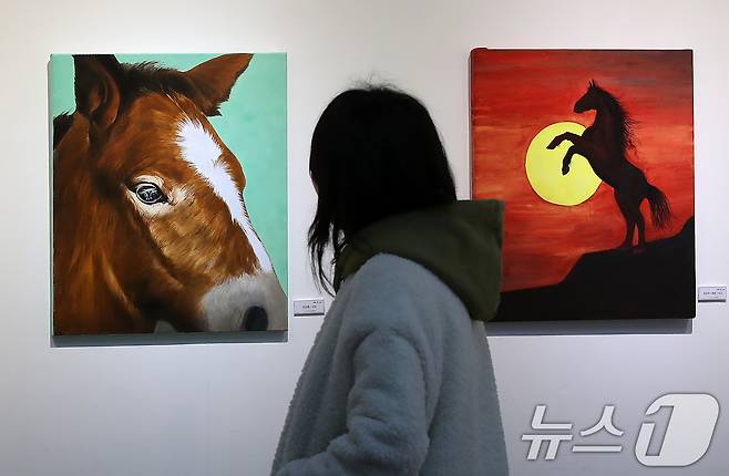 24일 대구 동구 아양아트센터에서 개막한 '2026 병오년(丙午年) 새해맞이 말(馬) 그림전'을 찾은 시민들이 역동적인 '붉은 말'의 해를 맞아 더 높이 비상하는 희망찬 새해를 기원하는 작품을 감상하고 있다. 2025.12.24/뉴스1 ⓒ News1 공정식 기자