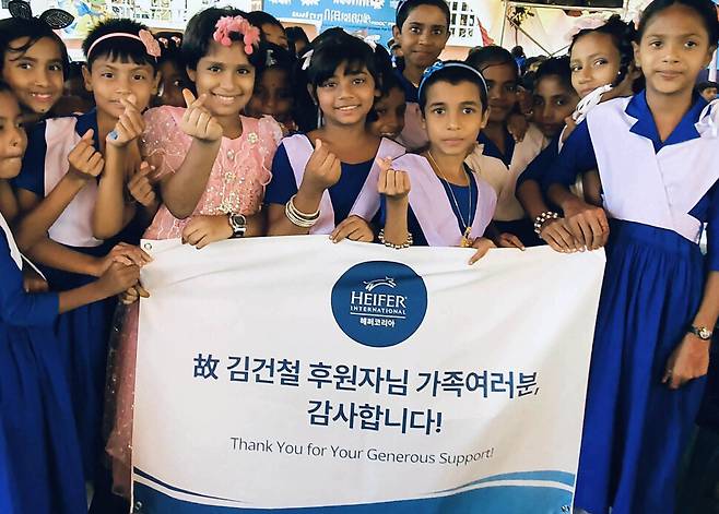 방글라데시 시라지간지 우토르 모혼푸르 공립초등학교에서 지난 1월 열린 ‘밀크 포 스쿨’ 행사에 참석한 학생들 이 고 김건철 후원자에게 감사를 표하는 배너를 들고 있다. 헤퍼코리아 제공