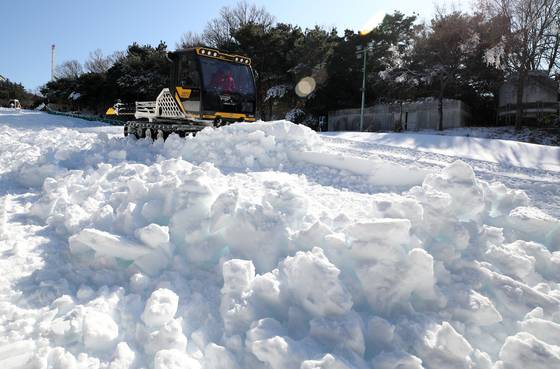 Employees level piled artificial snow to create a sledding slope at the E-World theme park in Dalseo District, Daegu, on Jan. 2, as a cold wave continues. [NEWS1]